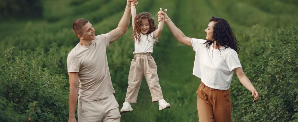 Joyful family moment in a green field during summer, capturing love and playfulness.