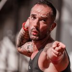 Tattooed man in a tank top points with focus during outdoor fitness activity in A Coruña.