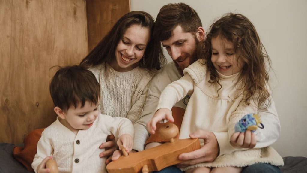 A joyful family of four playing together with a wooden toy indoors. Captures warmth and togetherness.