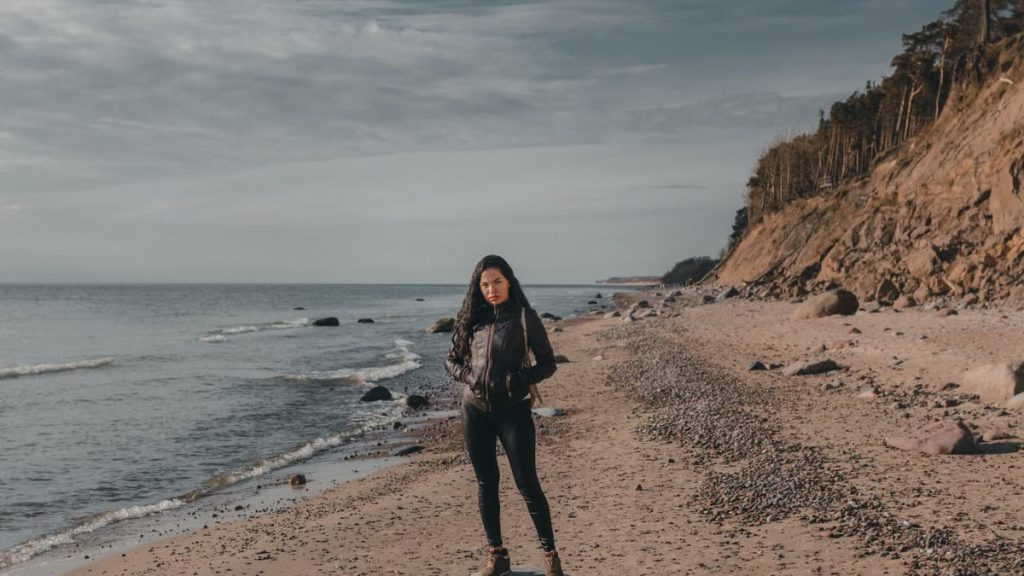 A woman standing on a peaceful Lithuanian beach by the Baltic Sea, showcasing a tranquil outdoor scenery.